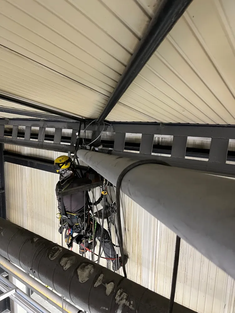 Zdjęcie przedstawia alpinistę przemysłowego podczas pracy na wysokości.