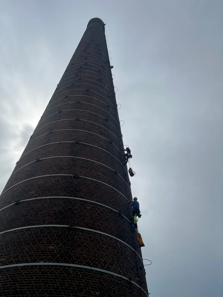 Zdjęcie przedstawia alpinistę przemysłowego podczas pracy na wysokości.