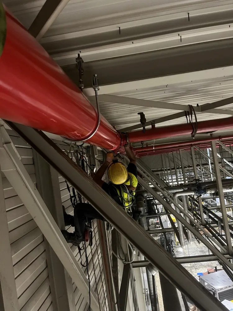 Zdjęcie przedstawia alpinistę przemysłowego podczas pracy na wysokości.